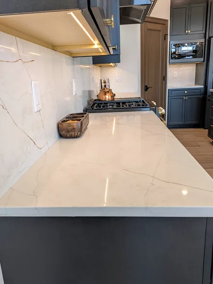 Close-up of a white quartz countertop with gold veining that continues into a full-height backsplash
